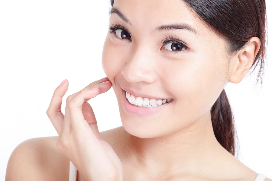 Beautiful young smiling woman hand touch her face and mouth lips teeth. Isolated over white background model is a asian girl