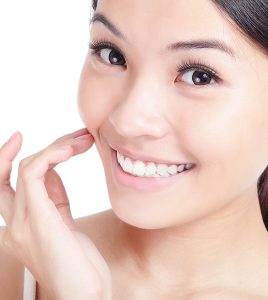 Beautiful young smiling woman hand touch her face and mouth lips teeth. Isolated over white background model is a asian girl